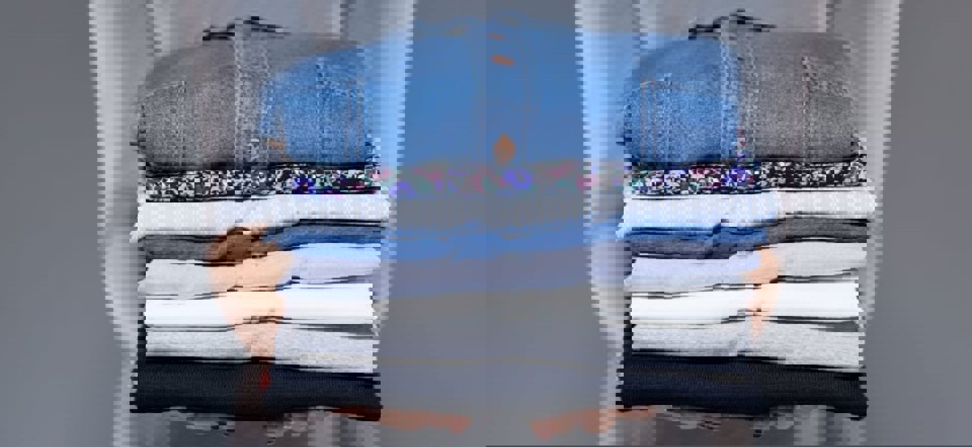 Woman Holding Stack Of Folded Laundry Min 1